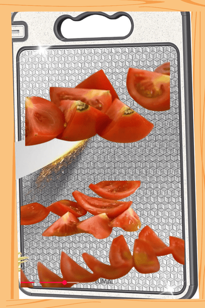 Imagem de uma tábua de cortes, material aço inoxidável. Mostrando a técnica do corte de tomates, específico para essa receita.